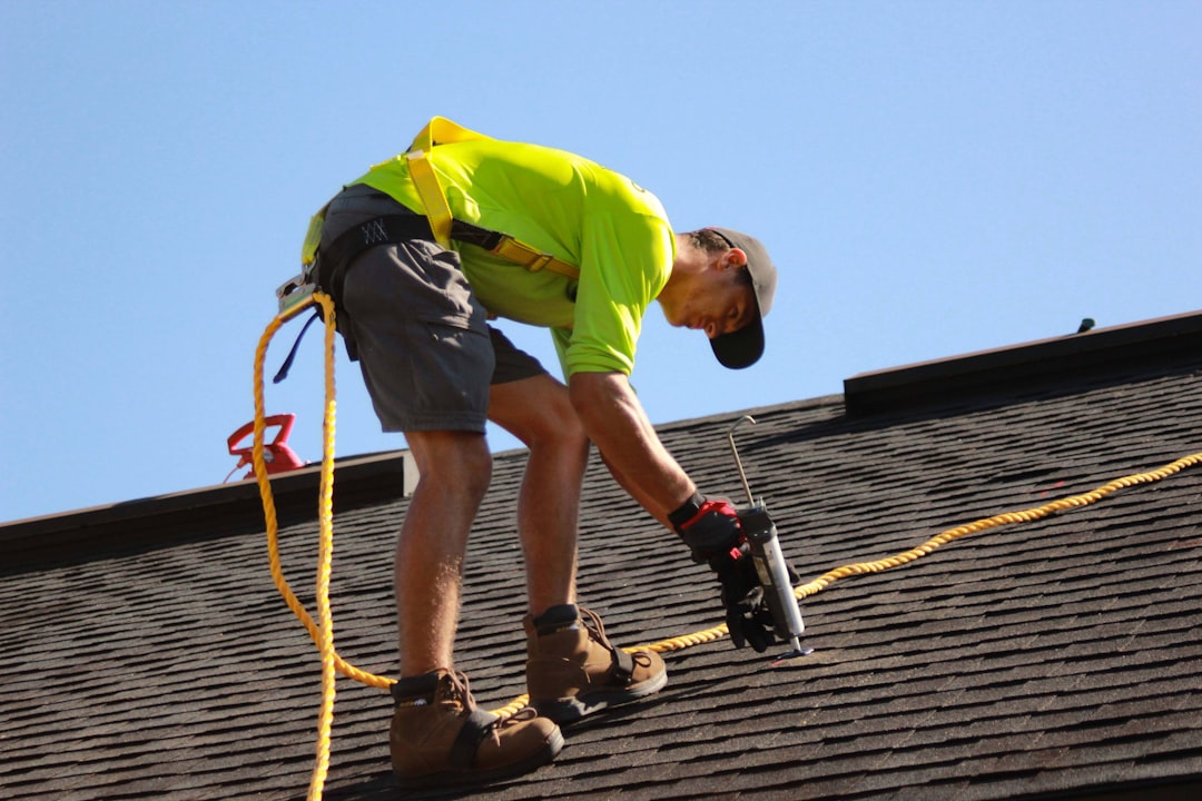Roofer in a harness fastening shingles on a residential roof